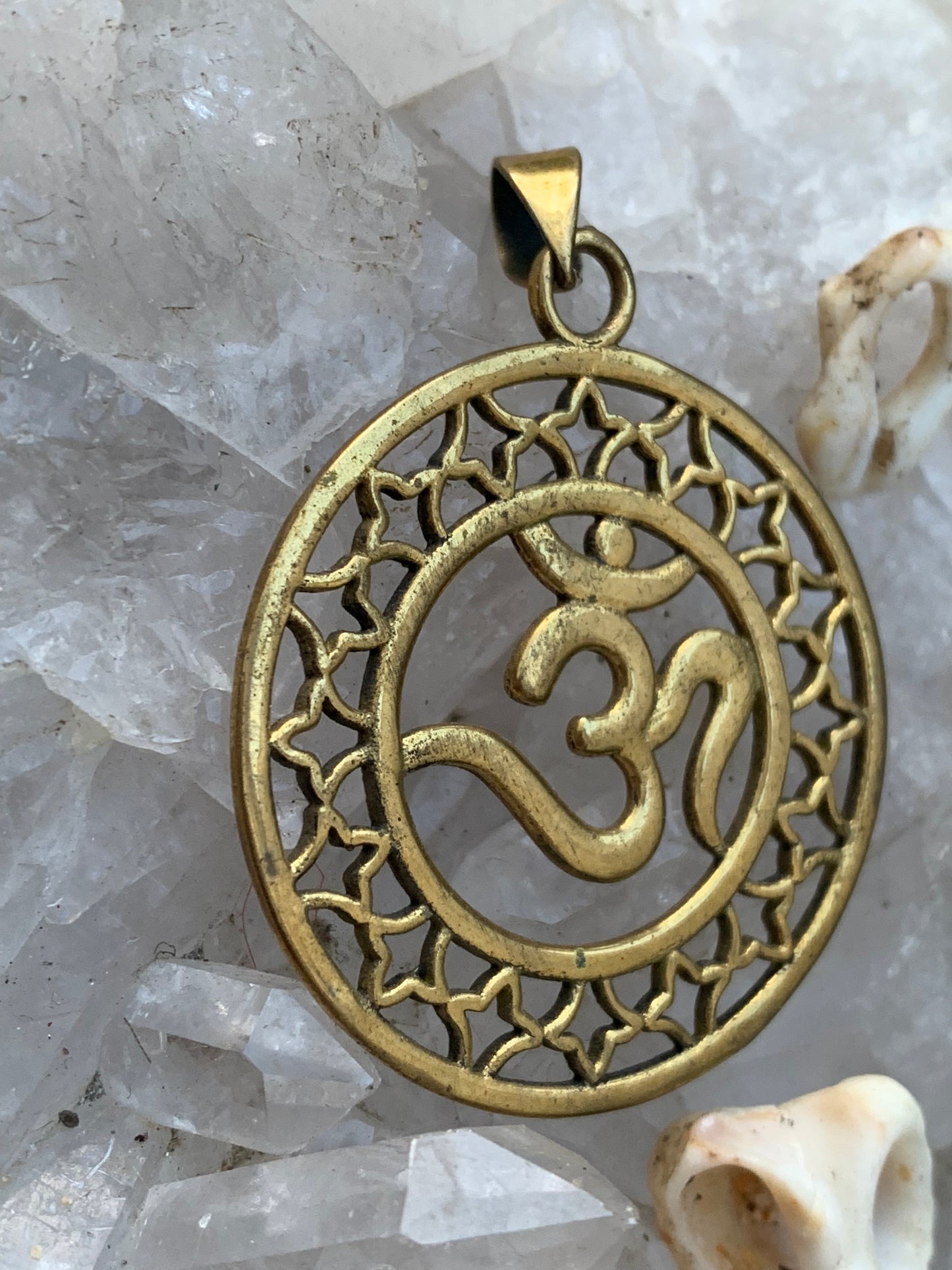 Om, pendentif en laiton doré de 3,6 centimètres de diamètre, vendu avec cordon noir réglable ! Tel un souffle ancien suspendu au creux du cœur, ce pendentif en laiton doré célèbre le symbole sacré Om, vibration originelle de l’univers !