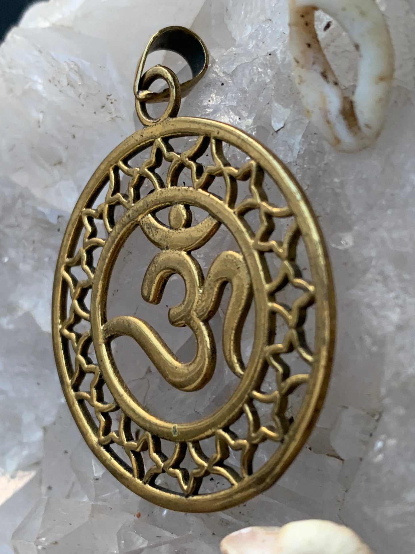 Om, pendentif en laiton doré de 3,6 centimètres de diamètre, vendu avec cordon noir réglable ! Tel un souffle ancien suspendu au creux du cœur, ce pendentif en laiton doré célèbre le symbole sacré Om, vibration originelle de l’univers !