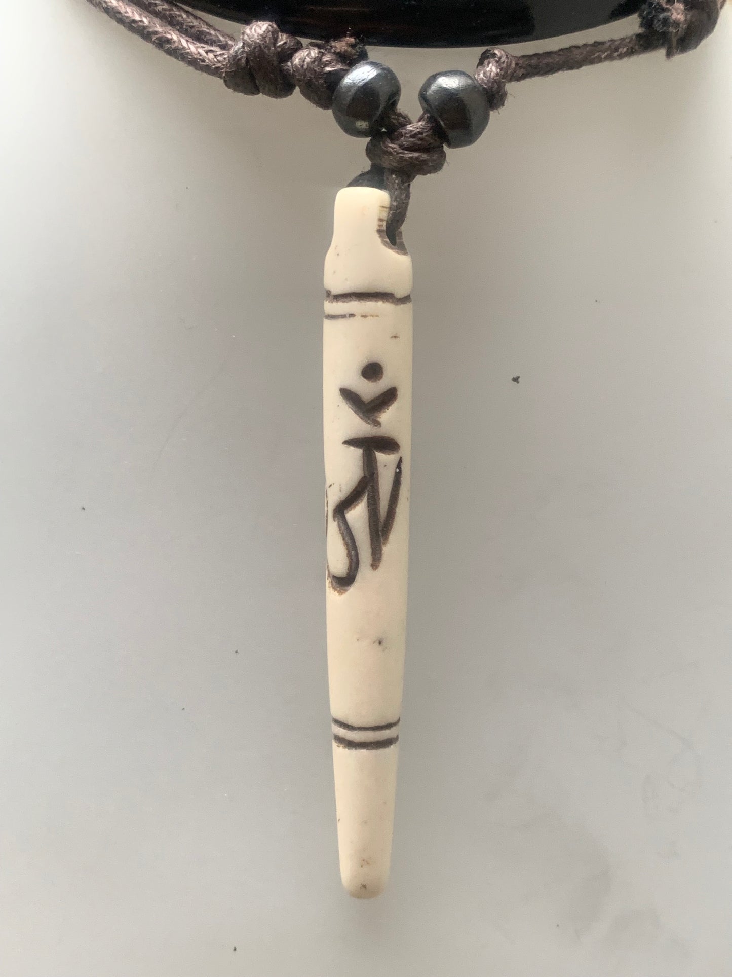 Elegant handcrafted pendant from Nepal, carved from bone with the sacred Om symbol, 60 millimeters high x 10 millimeters in diameter. Sold with a free adjustable black cord, perfect!