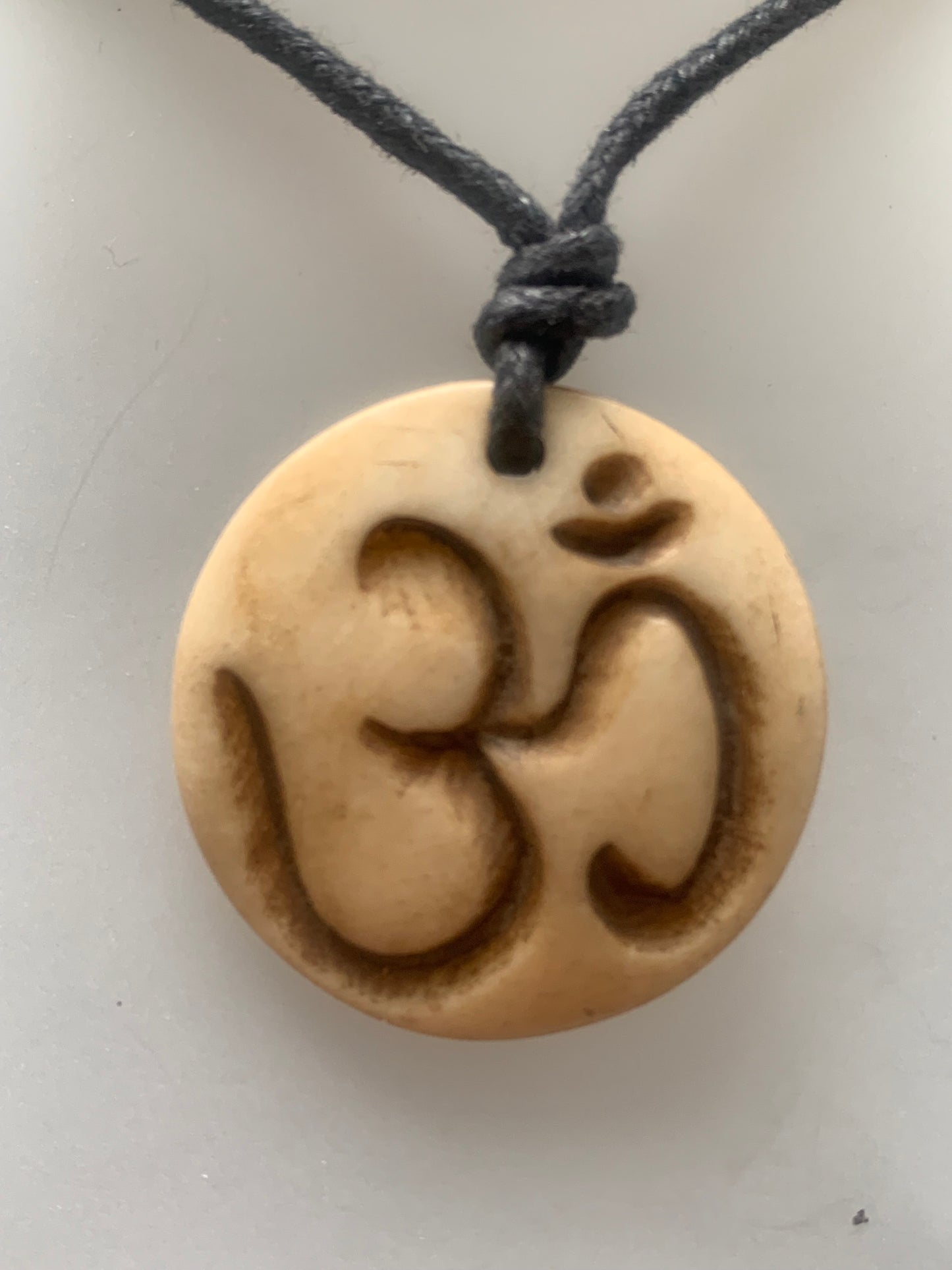 Handcrafted pendant from Nepal with Om symbol, carved from bone, 30 millimeters in diameter x 4 mm thick. Sold with a free adjustable black cord, perfect!