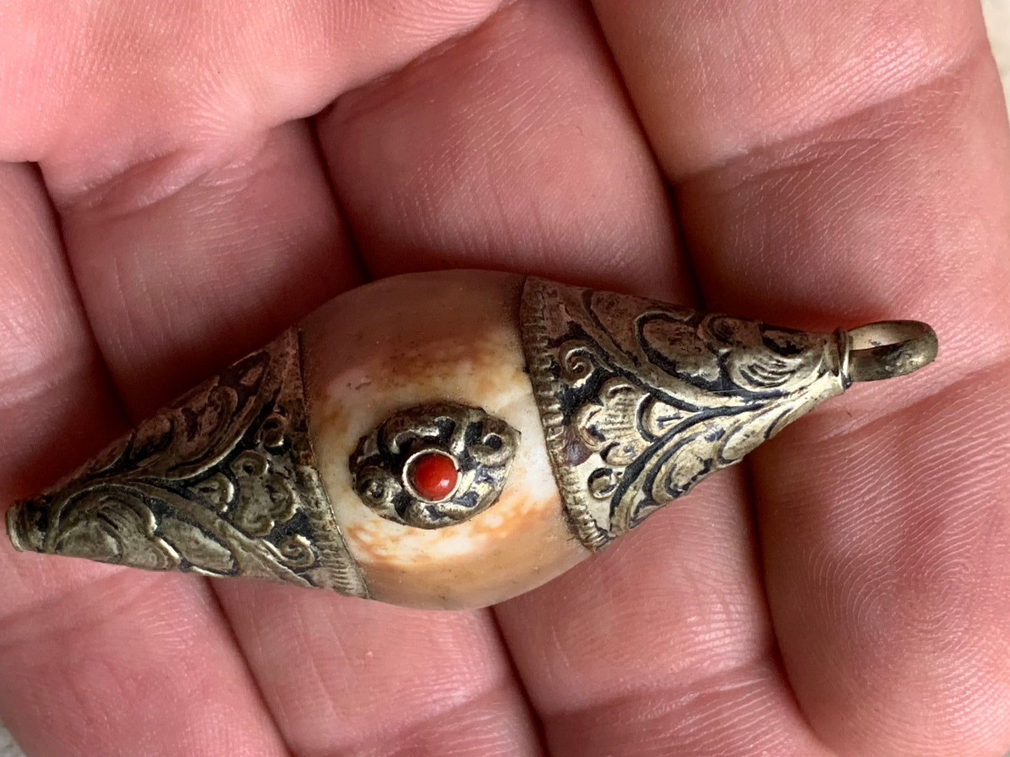 Handcrafted Nepalese shell pendant set in metal with pretty engravings and a coral bead! 60 millimeters high x 23 mm wide x 16 mm thick. Sold with a free adjustable black cord, perfect!
