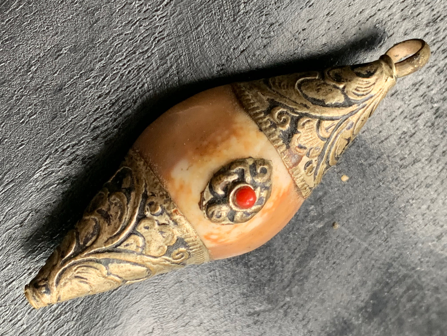 Handcrafted Nepalese shell pendant set in metal with pretty engravings and a coral bead! 60 millimeters high x 23 mm wide x 16 mm thick. Sold with a free adjustable black cord, perfect!