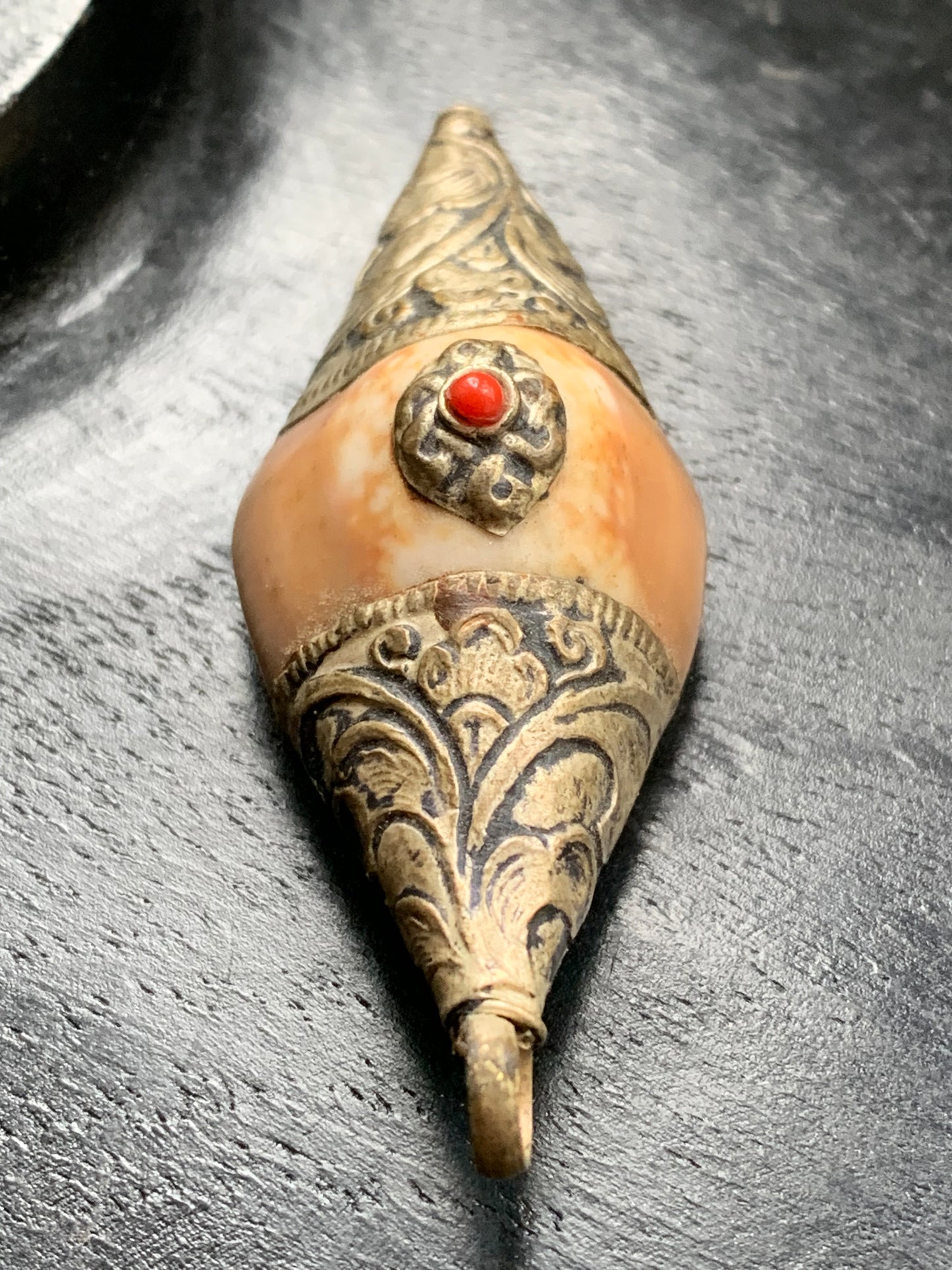 Handcrafted Nepalese shell pendant set in metal with pretty engravings and a coral bead! 60 millimeters high x 23 mm wide x 16 mm thick. Sold with a free adjustable black cord, perfect!