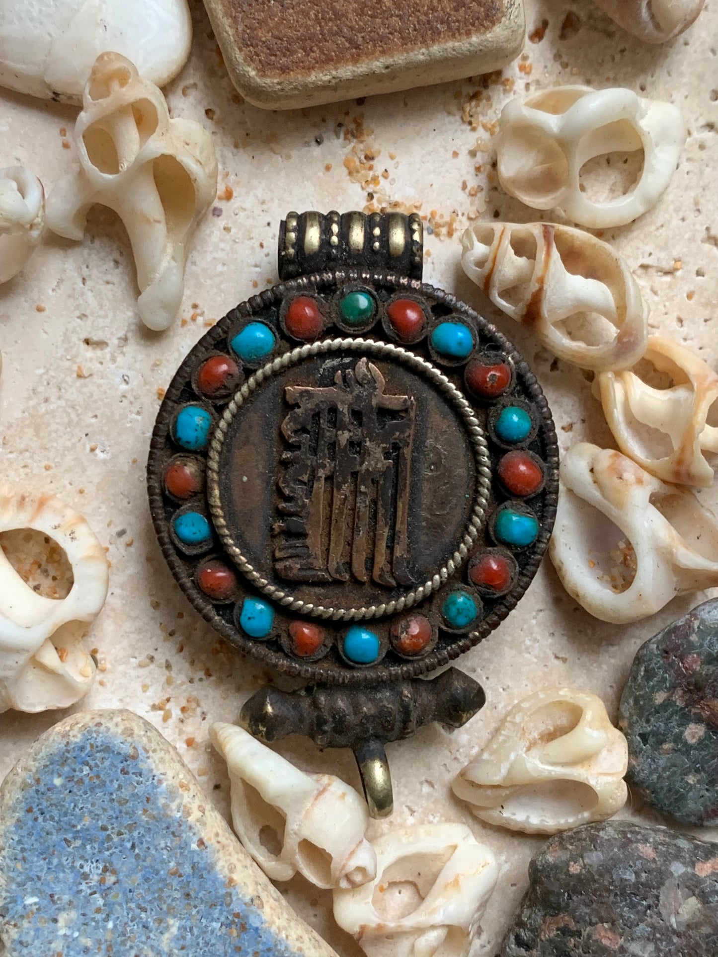 Pendentif/ Reliquaire artisanal du Népal avec pierres de turquoise et de corail sertis sur métal avec jolie gravure du Om ! De 52 millimètres de hauteur x 35 mm de largeur x 11 d'épaisseur. Vendu avec cordon noir réglable offert, parfait !