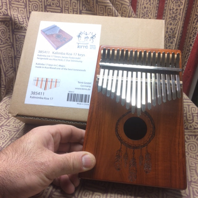 Kalimba 'Koa'/ Piano a doigt - 17 notes, fait en bois de koa (bois de résonance tropical) accordé en Do/ C majeur. Décoré d'un motif indien sculpté et est livrée avec un sac en tissu et un marteau d'accordage ! 23x19x7,5 cm !