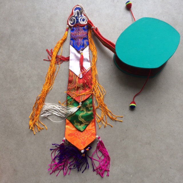 Damaru Tibétain ou 'tambour de mendiant'. Issu de rituels mystiques, joliment décoré de pampilles et de franges colorées, avec housse en brocart de soie !