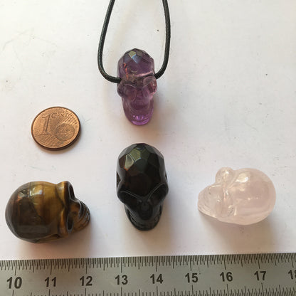 Pendentif en forme de crâne, symbole de la connaissance ! De 18 millimètres de hauteur x 16 mm de largeur. Pierre au choix : Améthyste, Obsidienne, Quartz rose, Oeil de tigre. Vendu avec cordon noir réglable offert, parfait !
