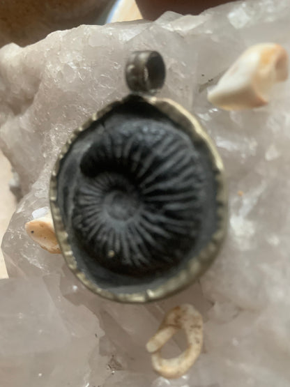 Fossilized ammonite from Nepal, measuring 45x35x12 millimeters. This authentic and unique piece reveals the natural spirals and fascinating patterns of this fossil. Comes with a drawstring, ready to wear or give as a gift!