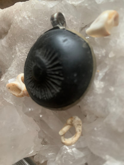 Fossilized ammonite from Nepal, measuring 45x35x12 millimeters. This authentic and unique piece reveals the natural spirals and fascinating patterns of this fossil. Comes with a drawstring, ready to wear or give as a gift!