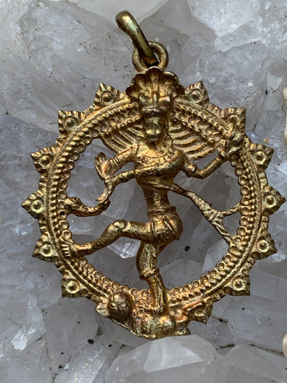 Pendentif en 'laiton argenté ou doré' de la divinité hindoue 'Shiva' sous sa forme de Shiva Nataraj. * Le roi (raja) de la danse (nata) est un symbole du mouvement éternel de l'univers, la danse cosmique. 4,5 cm de diamètre, vendu avec cordon !