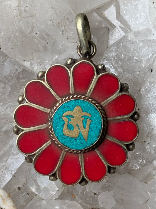 Corail et turquoise sertis sur pendentif en métal argenté de type laiton avec le symbole Om au centre. 30 millimètres de diamètre x 8 d'épaisseur. Vendu avec cordon noir réglable offert !