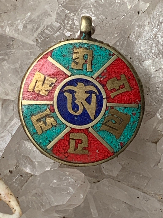 Corail, turquoise et lapis lazuli sertis sur pendentif en métal argenté de type laiton avec le symbole Om au centre. 30 millimètres de diamètre x 6 d'épaisseur. Vendu avec cordon noir réglable offert !