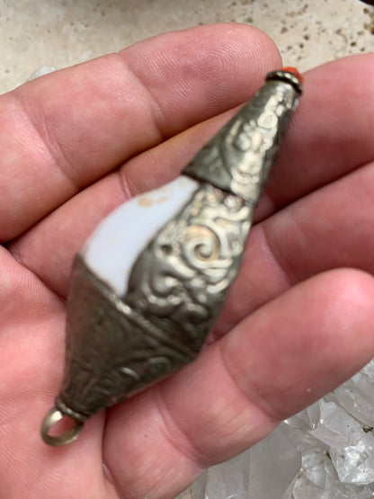 Handcrafted Nepalese shell pendant set in metal with beautiful engravings and a coral bead! 65 millimeters high x 28 mm in diameter. Sold with a free adjustable black cord, perfect!