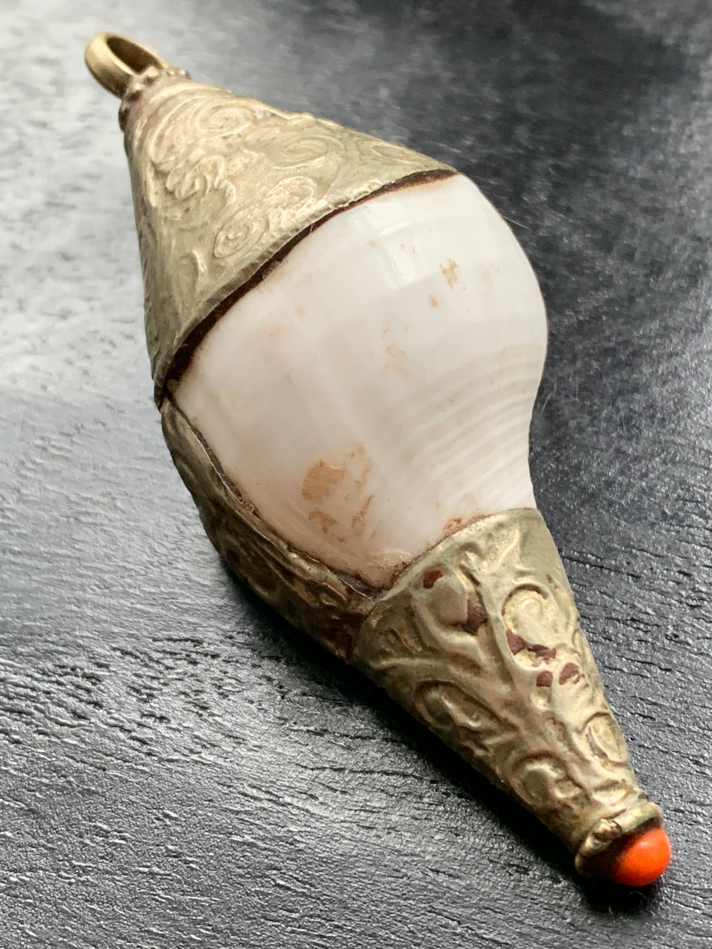 Handcrafted Nepalese shell pendant set in metal with beautiful engravings and a coral bead! 65 millimeters high x 28 mm in diameter. Sold with a free adjustable black cord, perfect!