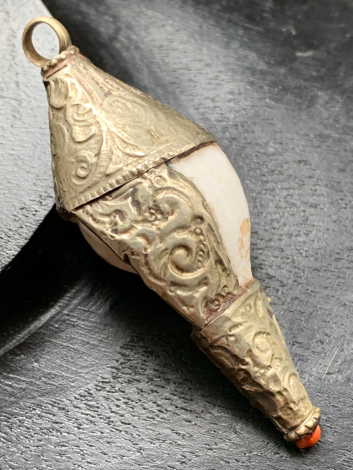 Handcrafted Nepalese shell pendant set in metal with beautiful engravings and a coral bead! 65 millimeters high x 28 mm in diameter. Sold with a free adjustable black cord, perfect!