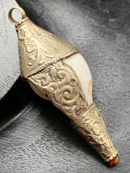 Handcrafted Nepalese shell pendant set in metal with beautiful engravings and a coral bead! 65 millimeters high x 28 mm in diameter. Sold with a free adjustable black cord, perfect!