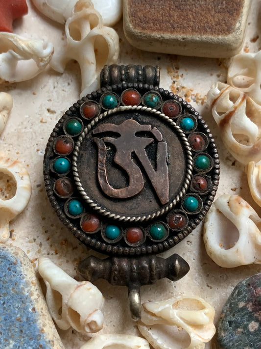 Pendentif/ Reliquaire artisanal du Népal avec pierres de turquoise et de corail sertis sur métal avec jolie gravure du Om ! De 52 millimètres de hauteur x 35 mm de largeur x 11 d'épaisseur. Vendu avec cordon noir réglable offert, parfait !