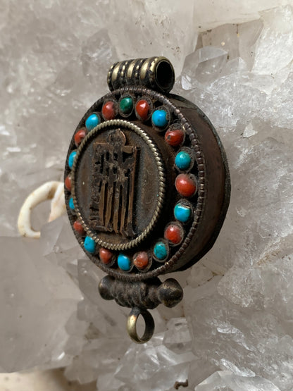 Pendentif/ Reliquaire artisanal du Népal avec pierres de turquoise et de corail sertis sur métal avec jolie gravure du Om ! De 52 millimètres de hauteur x 35 mm de largeur x 11 d'épaisseur. Vendu avec cordon noir réglable offert, parfait !