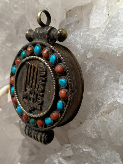 Pendentif/ Reliquaire artisanal du Népal avec pierres de turquoise et de corail sertis sur métal avec jolie gravure du Om ! De 52 millimètres de hauteur x 35 mm de largeur x 11 d'épaisseur. Vendu avec cordon noir réglable offert, parfait !