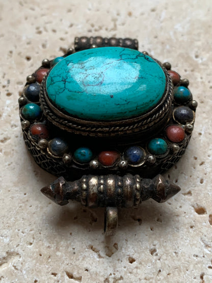 Pendentif/ Reliquaire artisanal du Népal avec pierres de turquoise et de corail sertis sur métal ! De 48 millimètres de hauteur x 37 mm de largeur x 18 d'épaisseur. Vendu avec cordon noir réglable offert, parfait !