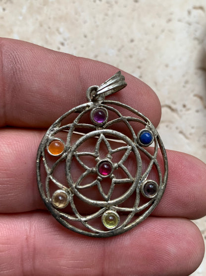 Pendentif '7 chakras' de 35 millimètres de diamètre, en métal argenté (laiton). Vendu avec cordon réglable de couleur noire !