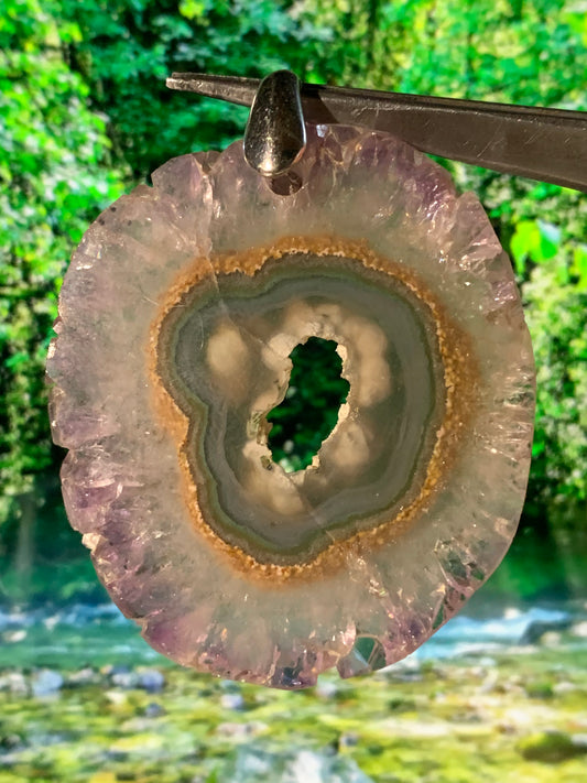 Améthyste, pendentif en 'tranche' de 57 mm de hauteur x 46 de largeur x 6 d'épaisseur. Vendu avec cordon réglable de couleur noire offert !