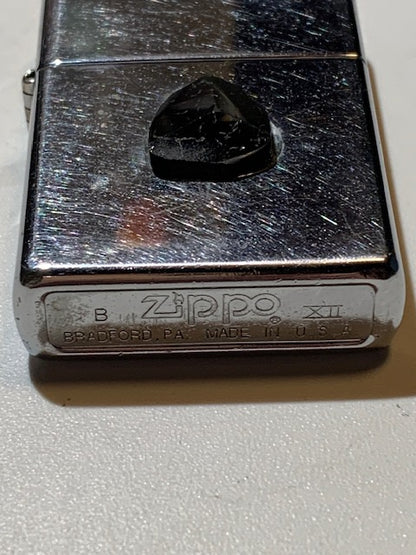 Briquet Zippo (B – XII), métal argenté, avec cabochon en tourmaline collé. Dimensions : 5 × 4 × 1 cm. Poids : 58,5 g.